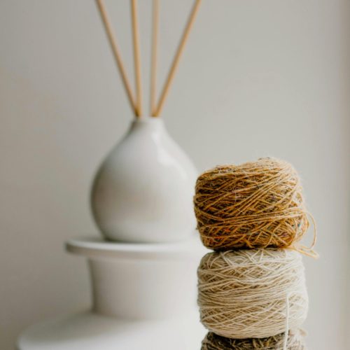 Minimalist arrangement of yarn balls and knitting needles in soft natural light, ideal for craft and knitting enthusiasts.